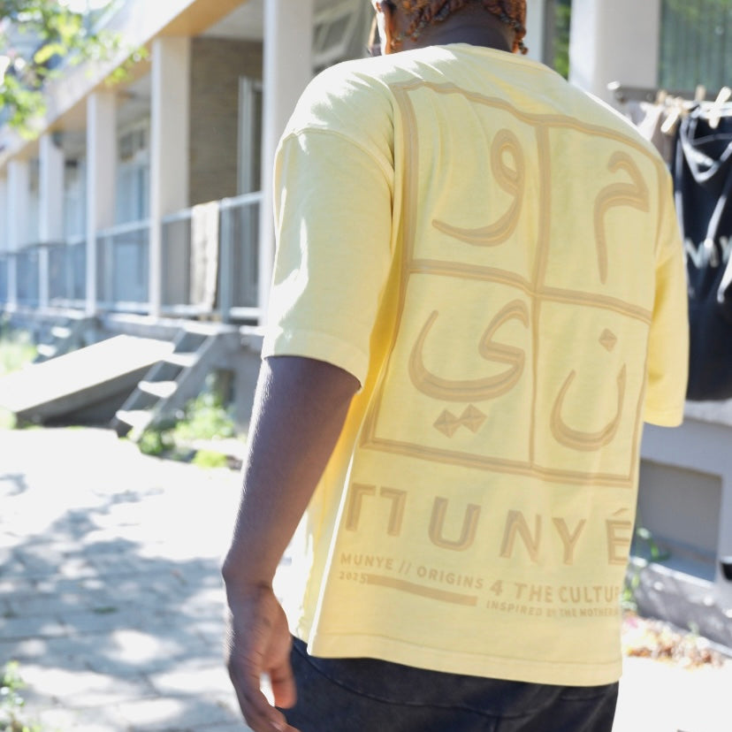 Person wearing a yellow t-shirt with text on the back, standing outdoors.